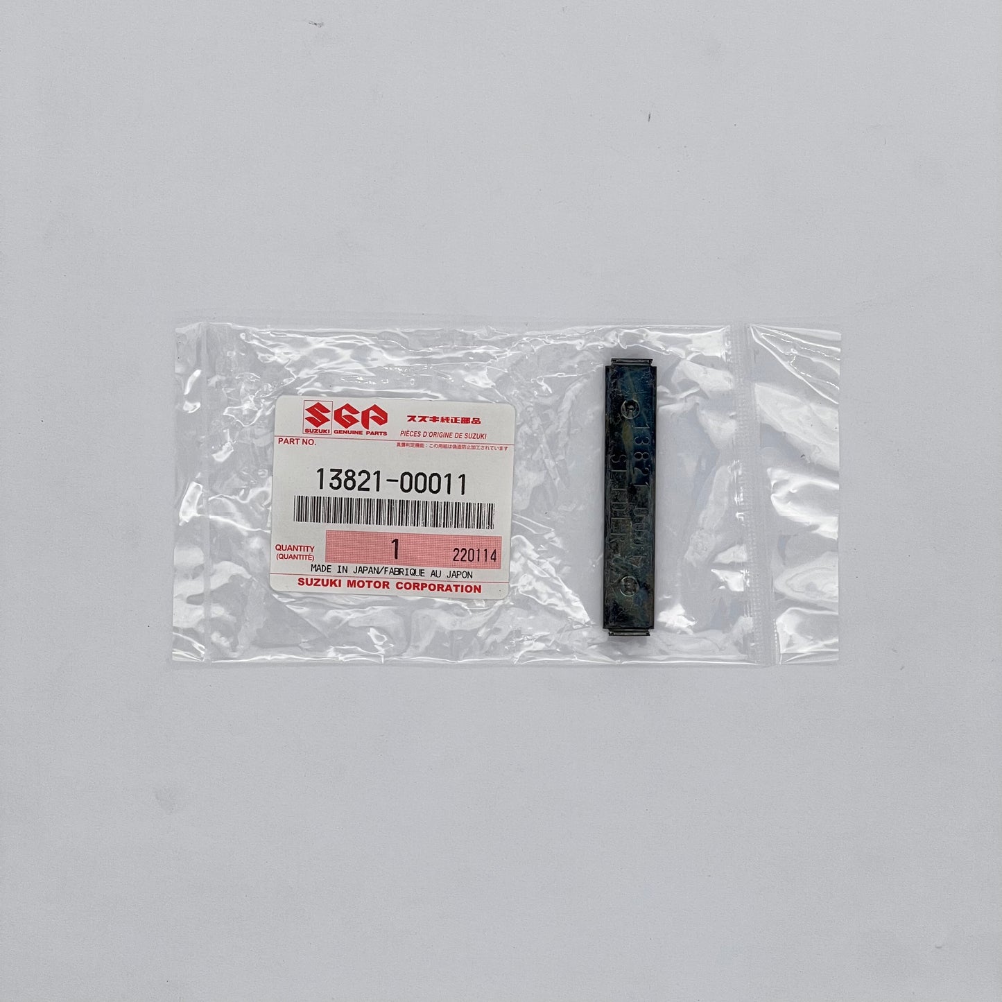 Suzuki part in packaging with a label on a gray background