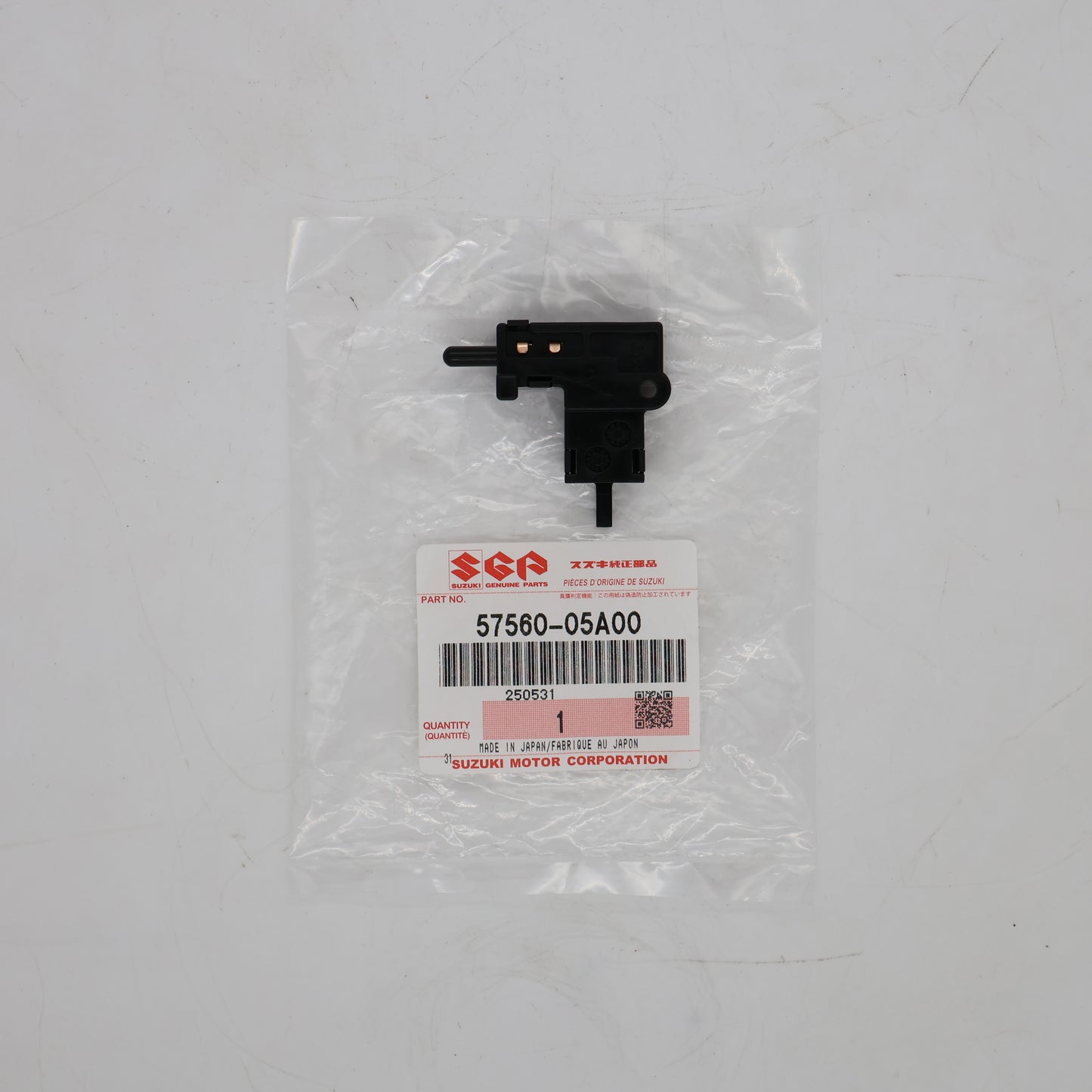 Black mechanical part in clear packaging with Suzuki label on a gray background