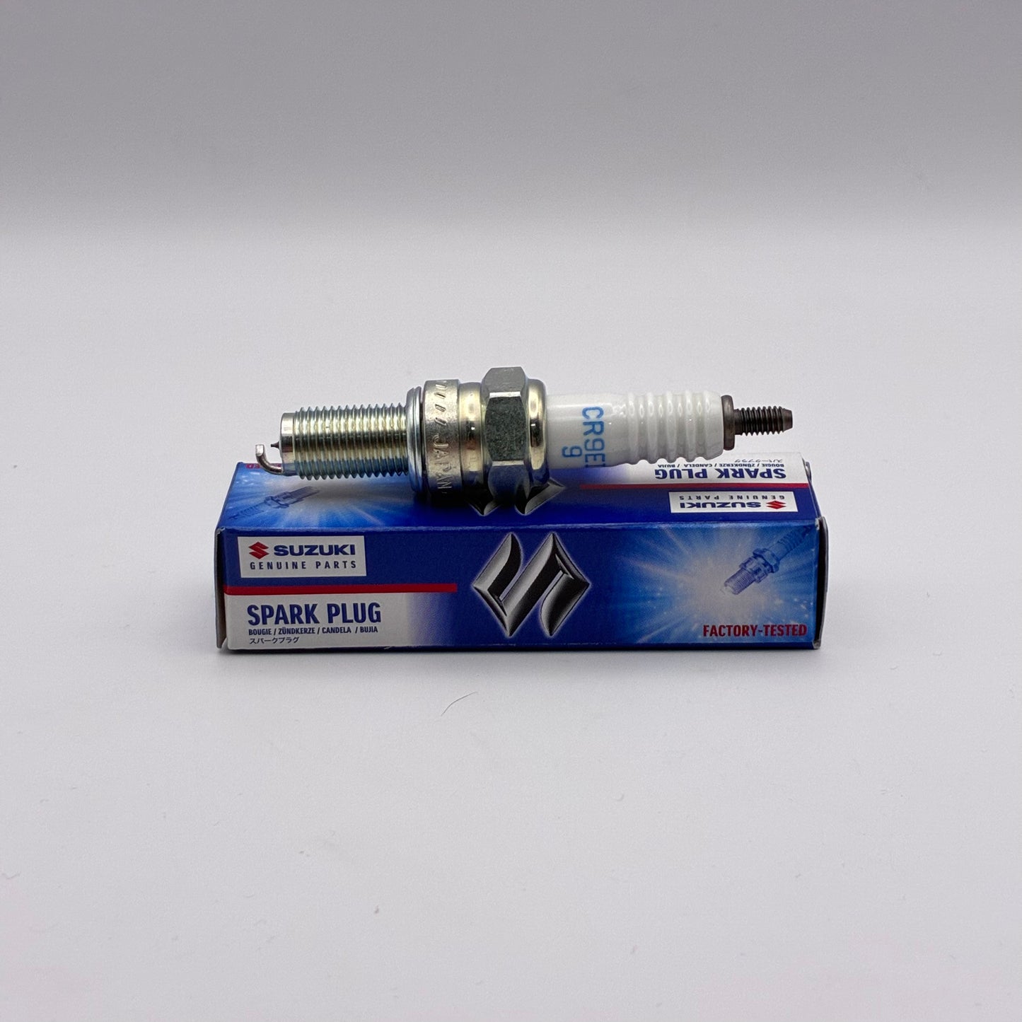 Suzuki spark plug and its packaging on a white background