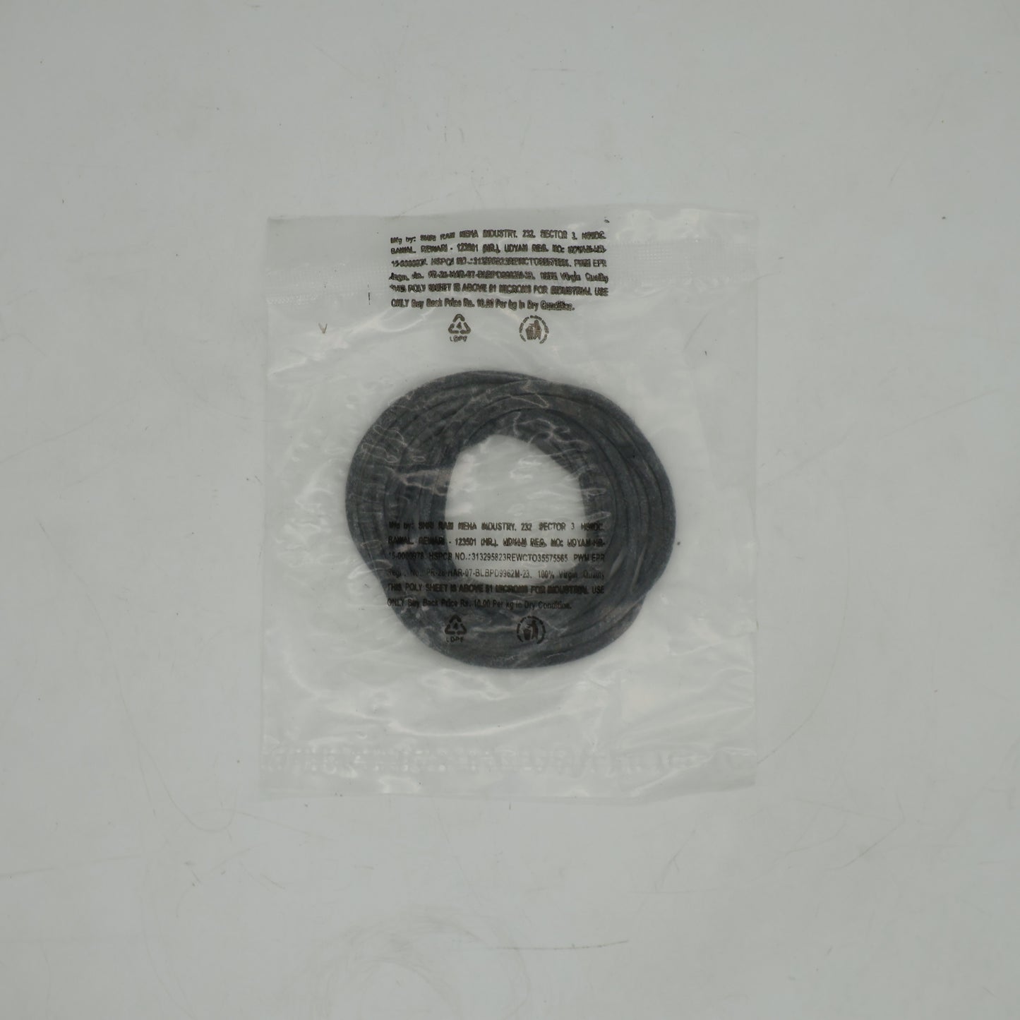 Black circular object in clear plastic packaging on a gray background