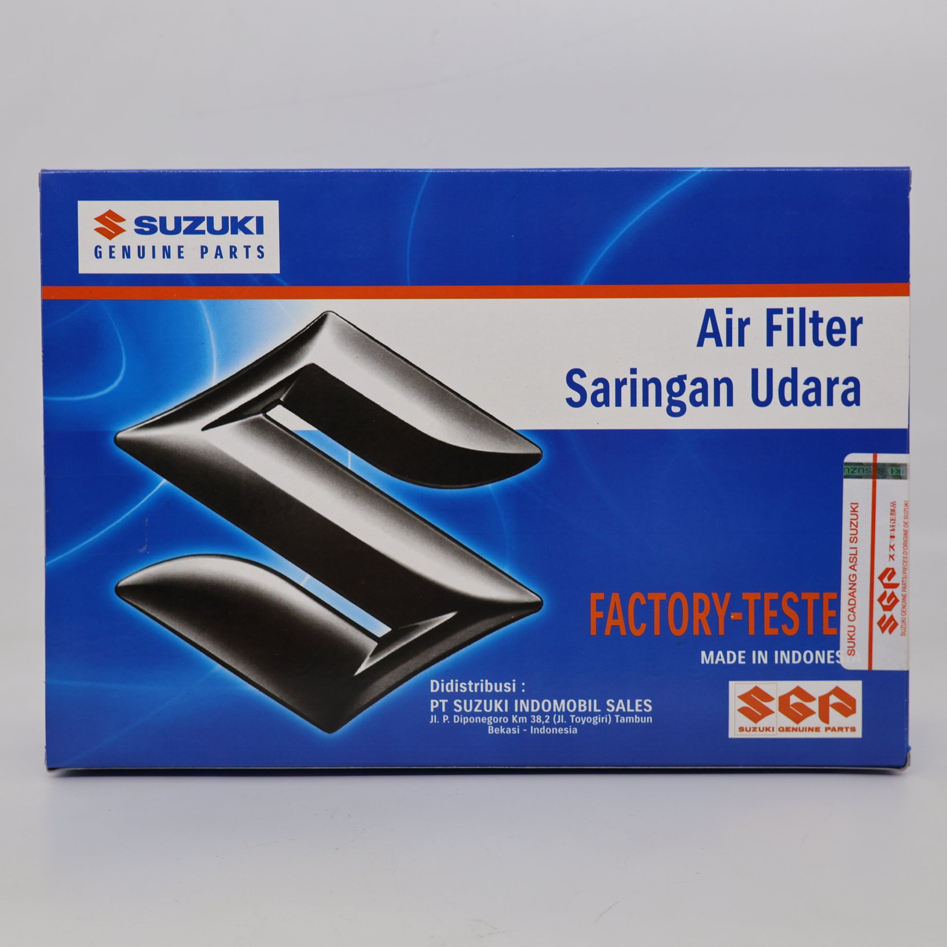 Suzuki genuine air filter packaging box, featuring a blue background with a large black stylized Suzuki logo and text reading 'Air Filter Saringan Udara' and 'Factory-Teste'.
