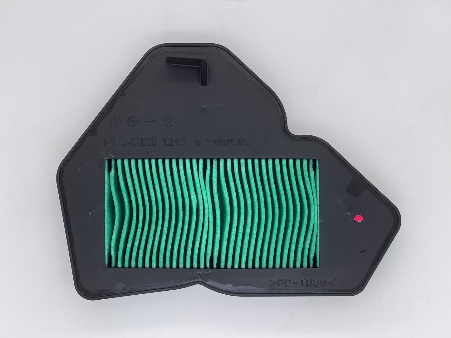 Green air filter in a black housing on a white background