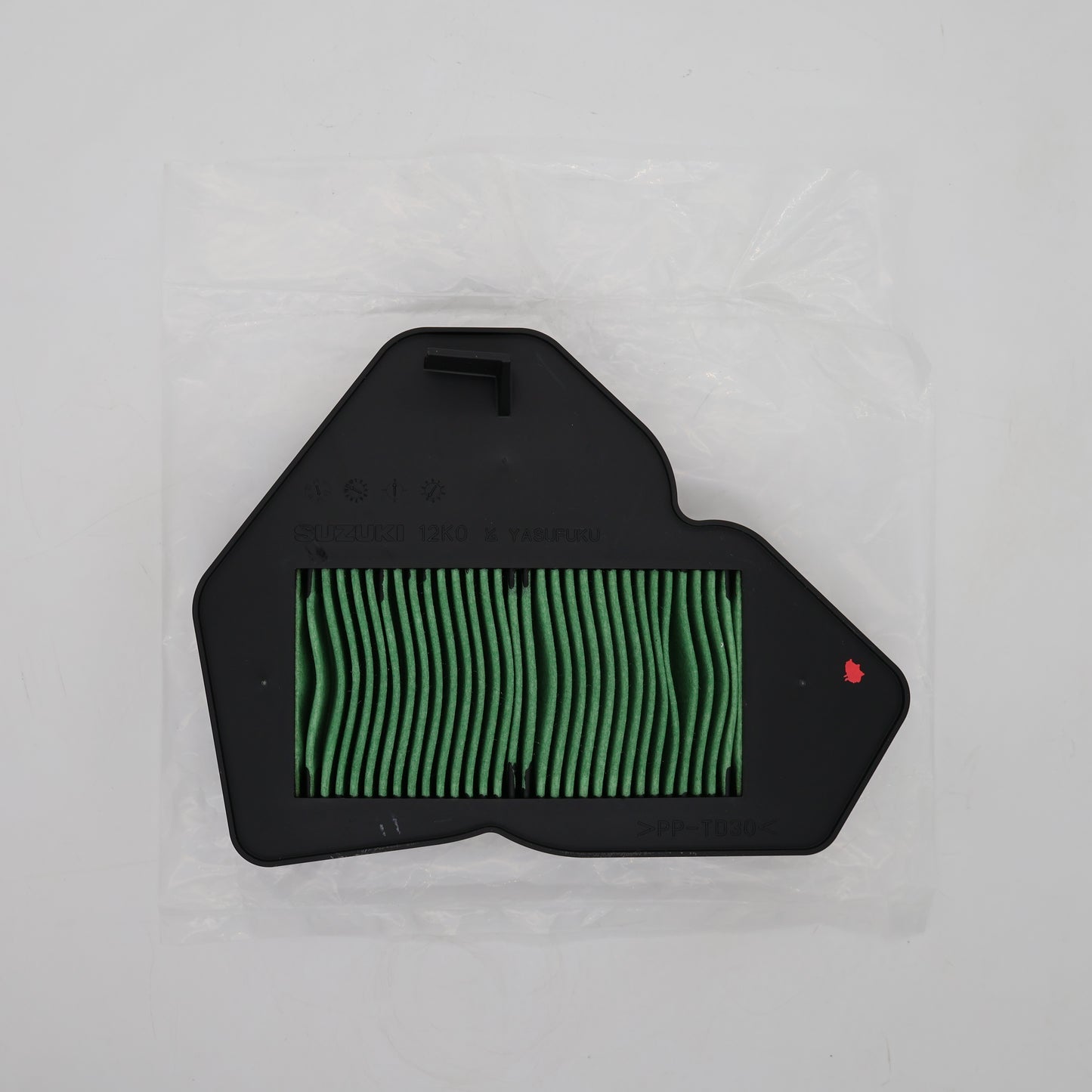 A replacement air filter with a black plastic frame and green pleated filter media, sealed in a clear plastic bag on a light gray background.