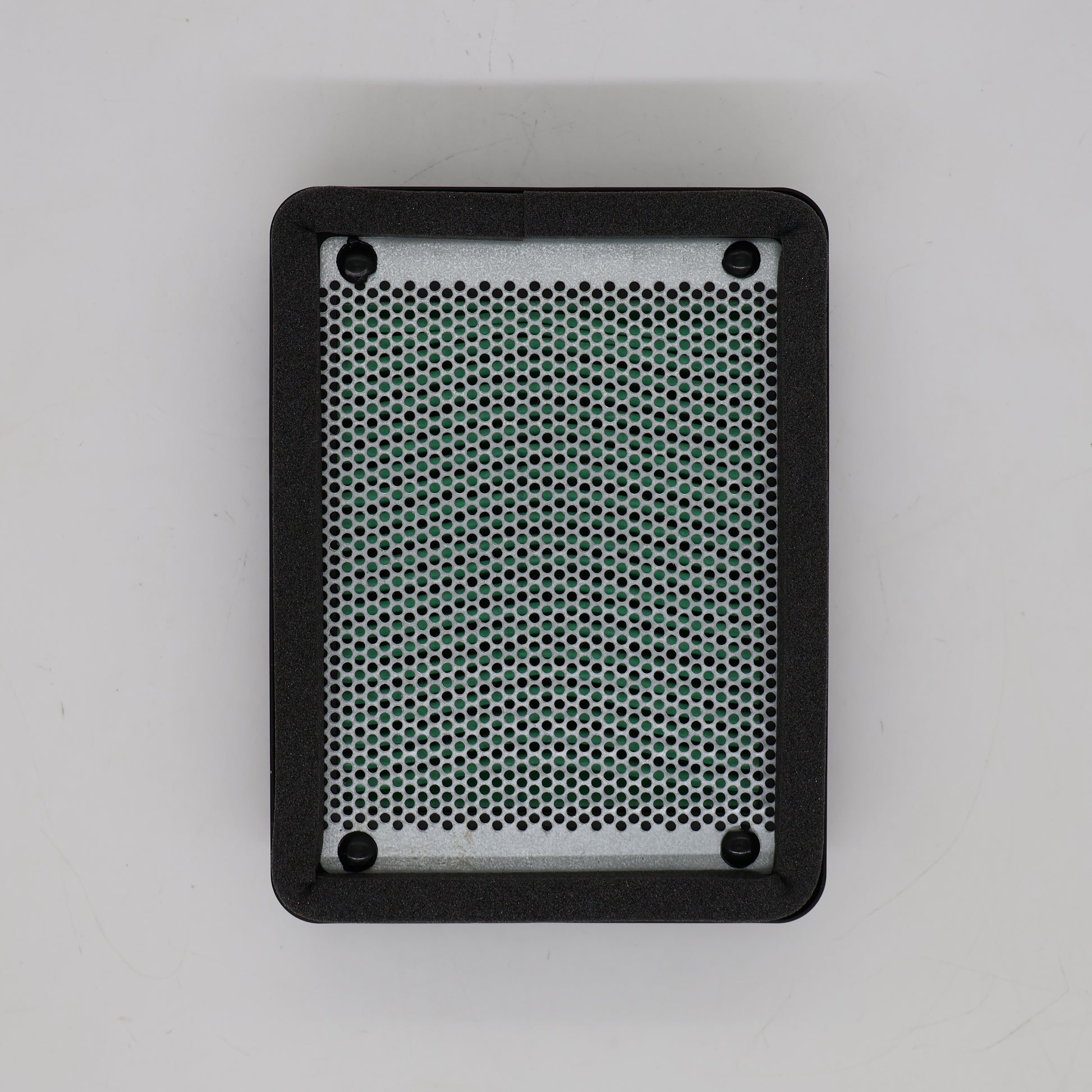 A rectangular black speaker grille cover with rounded corners, featuring a silver metal mesh center and four mounting holes, shown from a top-down view on a light gray background.
