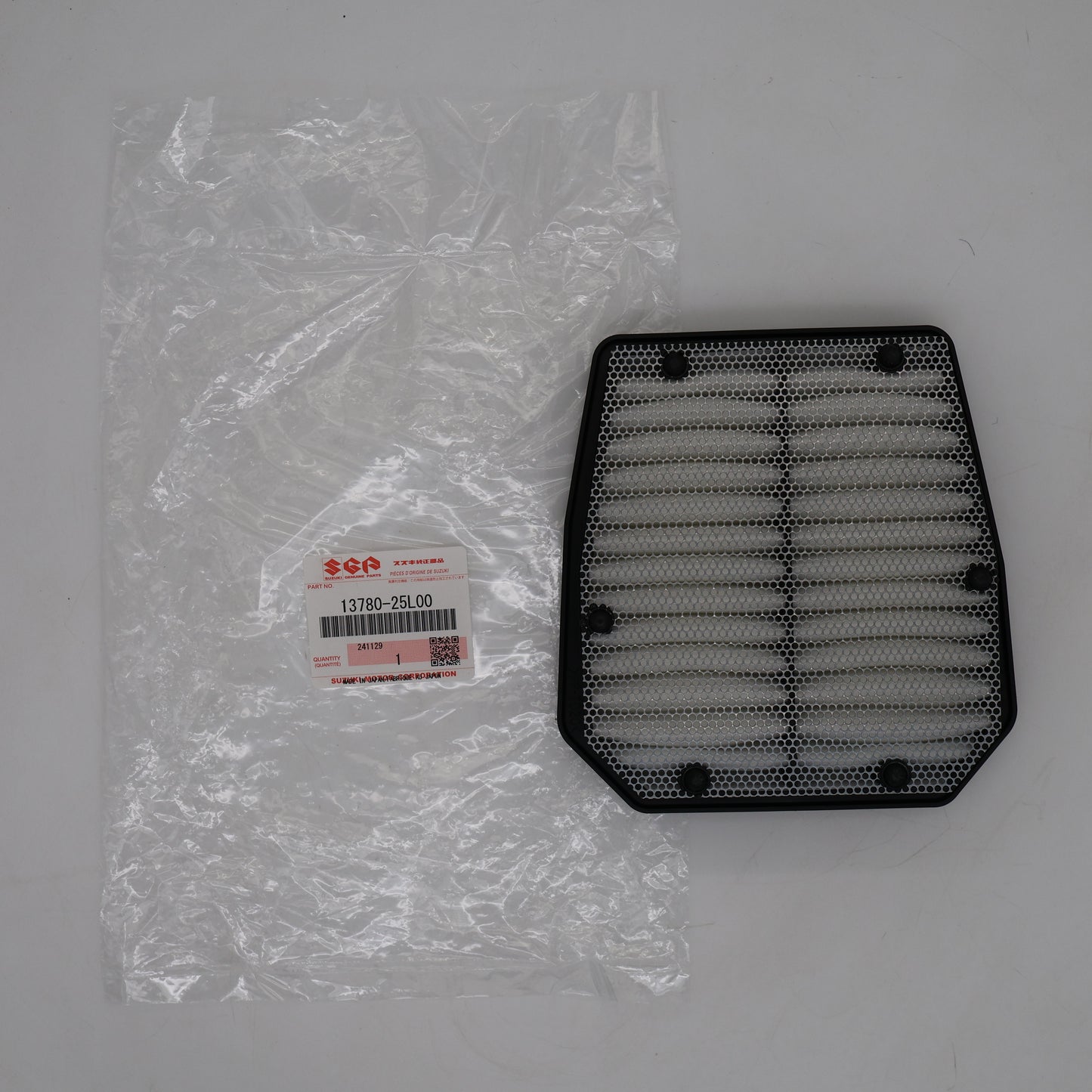 Black air filter next to its packaging on a gray background