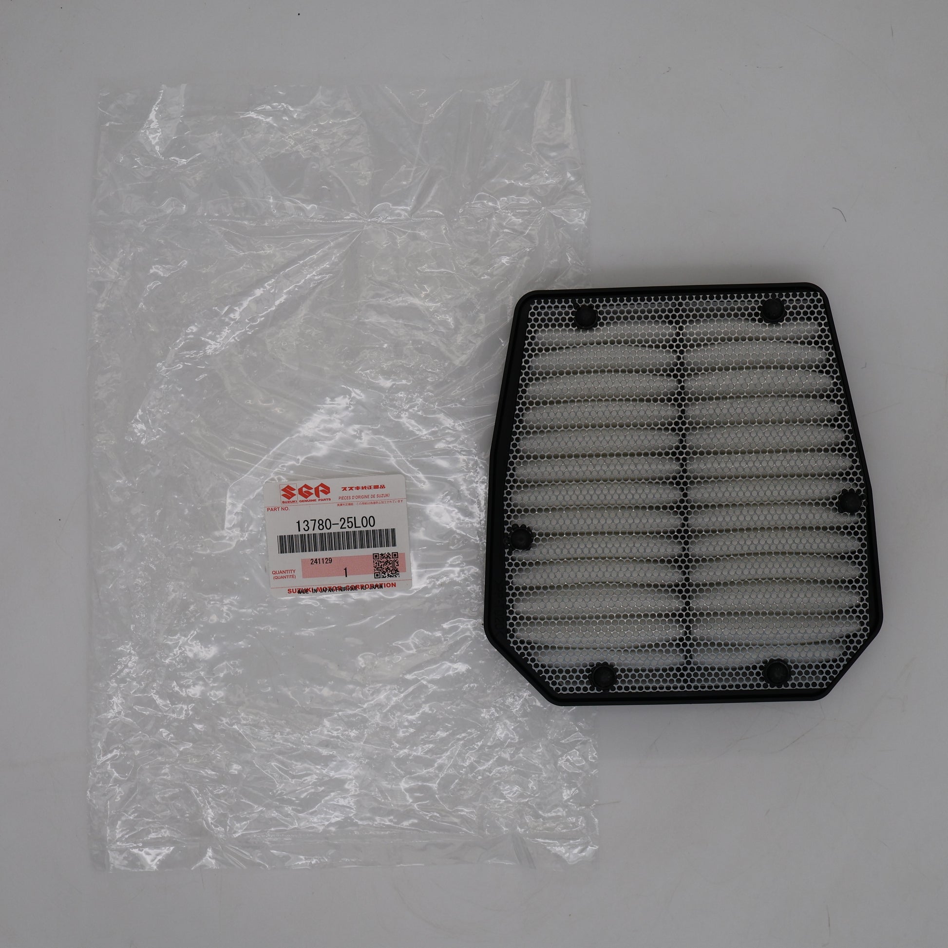 Black air filter next to its packaging on a gray background