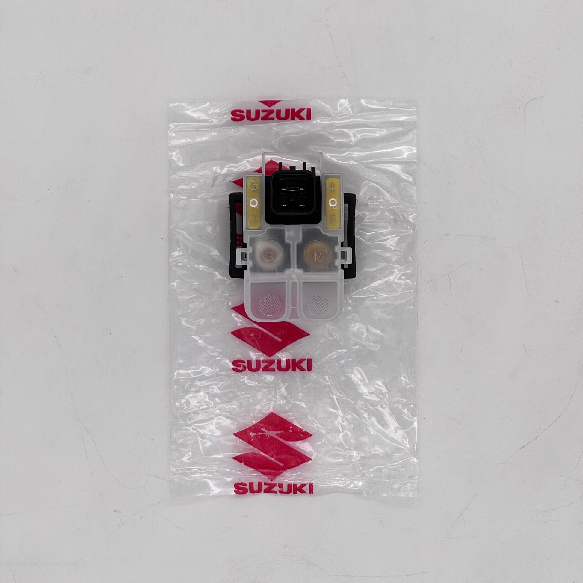Suzuki car part in clear packaging on a white background