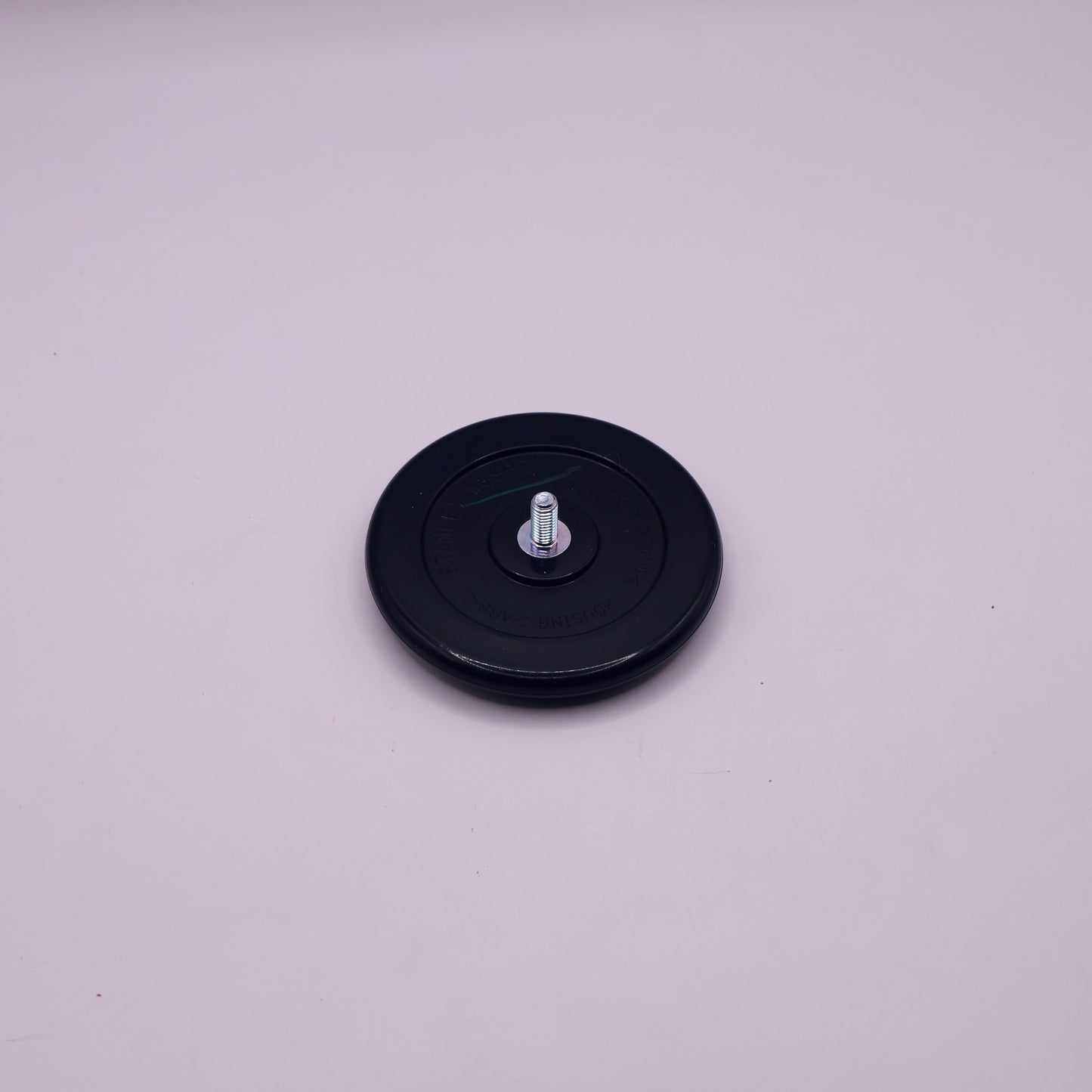 Black round object with a central screw on a light gray background