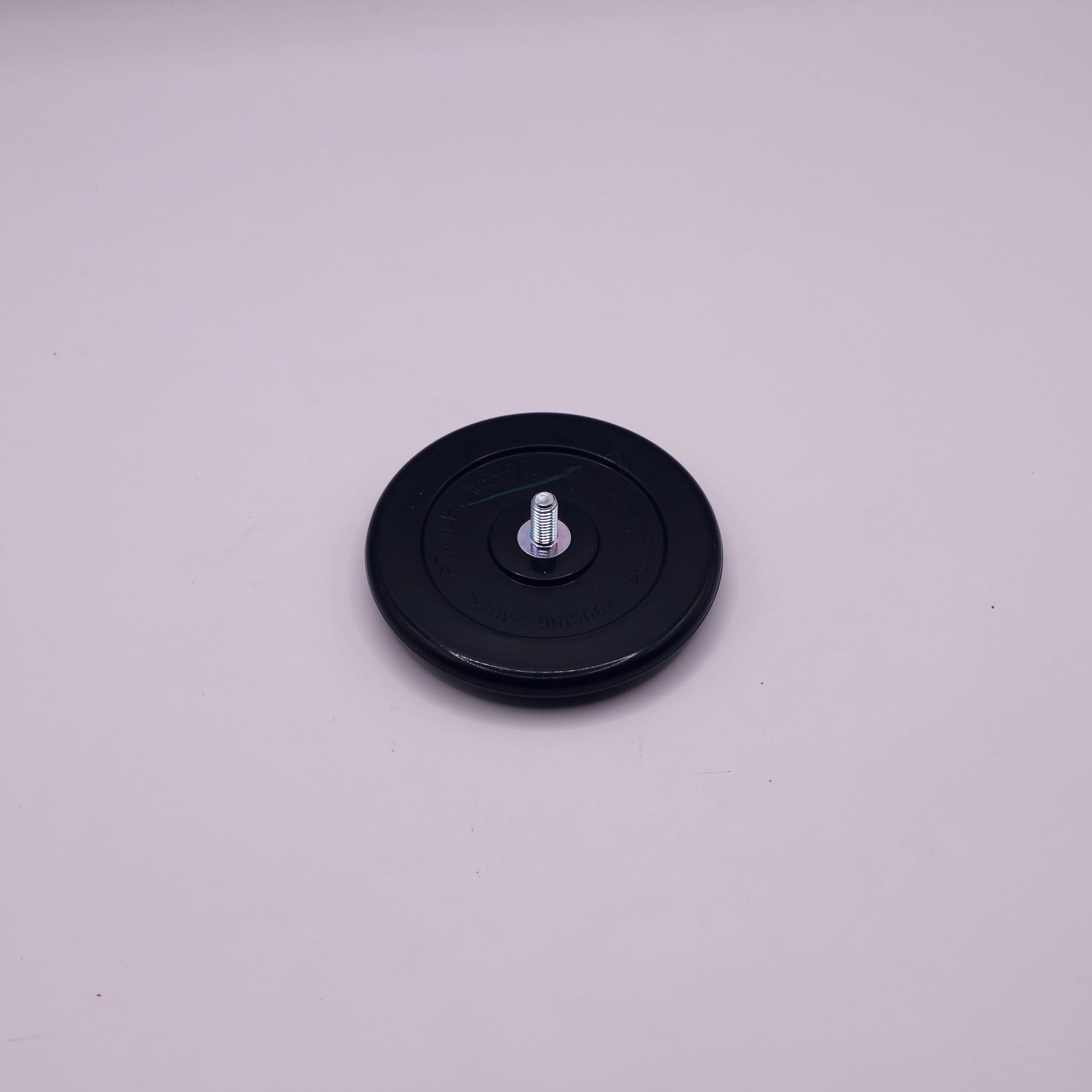 Black round object with a central screw on a light gray background